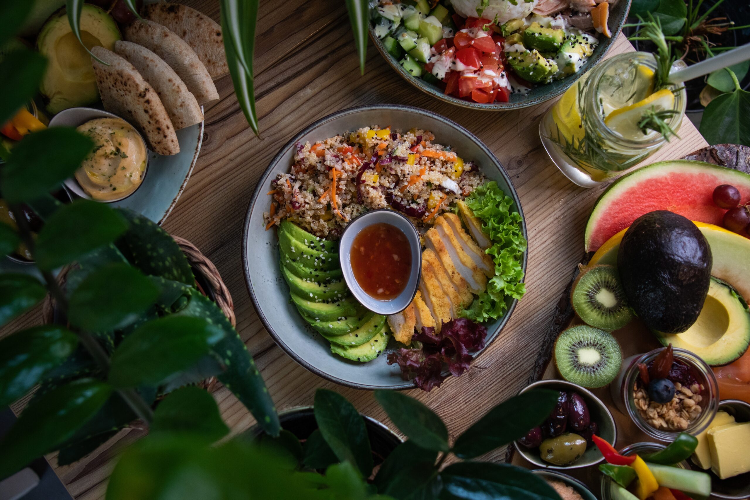 A high angle shot of plates of salad and fresh fruits and vegetable on a wooden surface